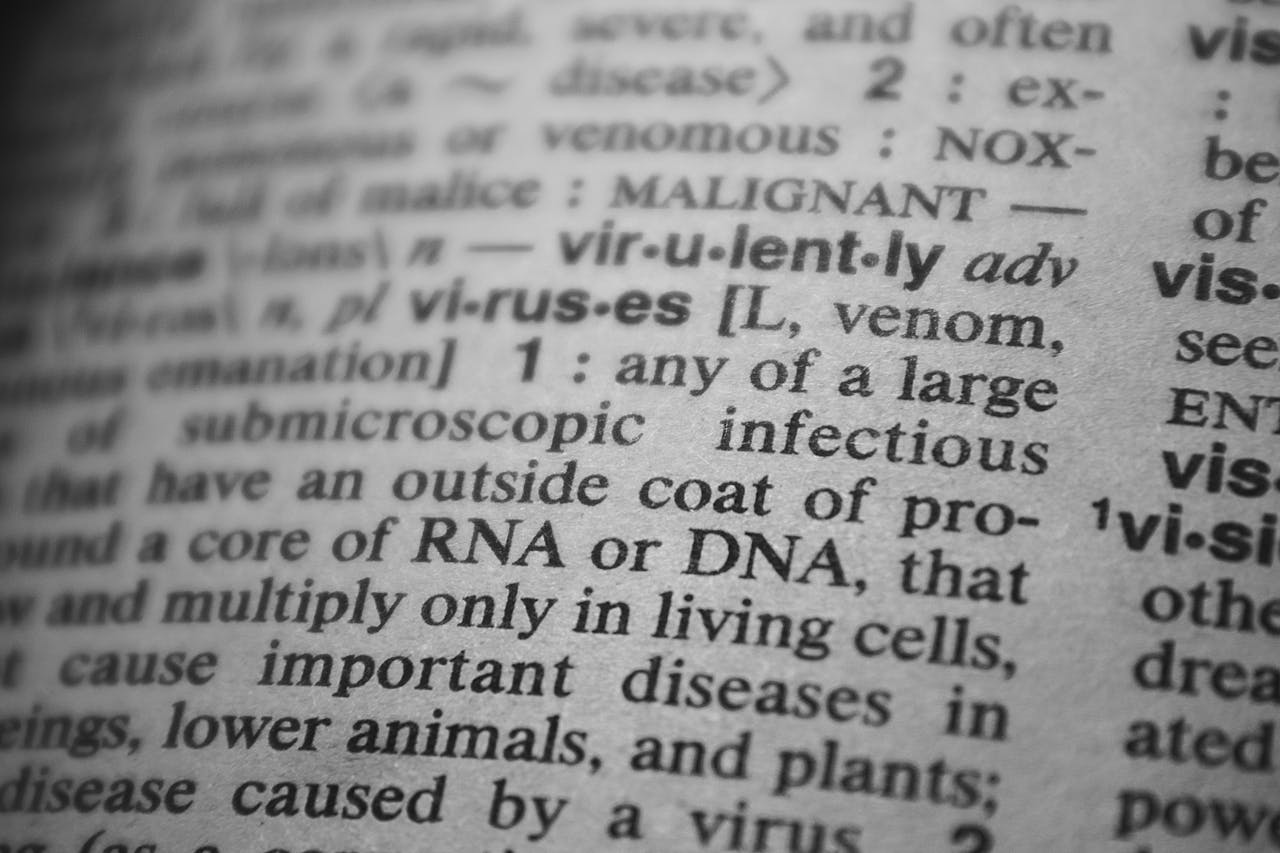 Black and white close-up of a dictionary page focusing on the definition of virus.